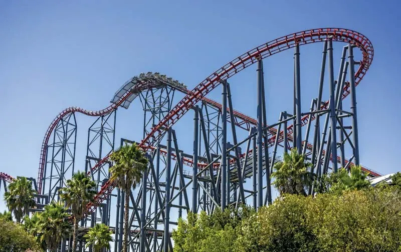Tall red and steel coaster among palm trees